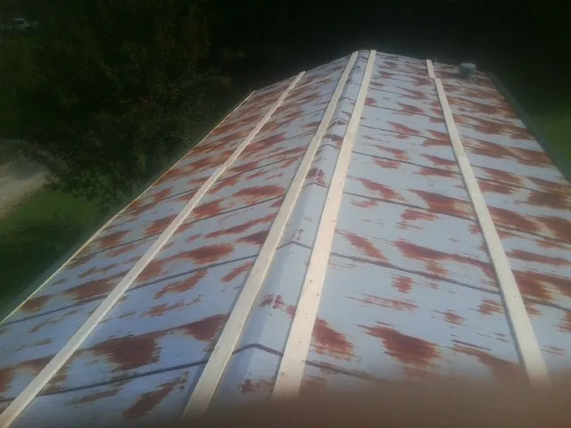 Rusted metal roof panels with new wood purlins before replacement — Storm Damage Roof Repair in Thorp by Roofing Brothers