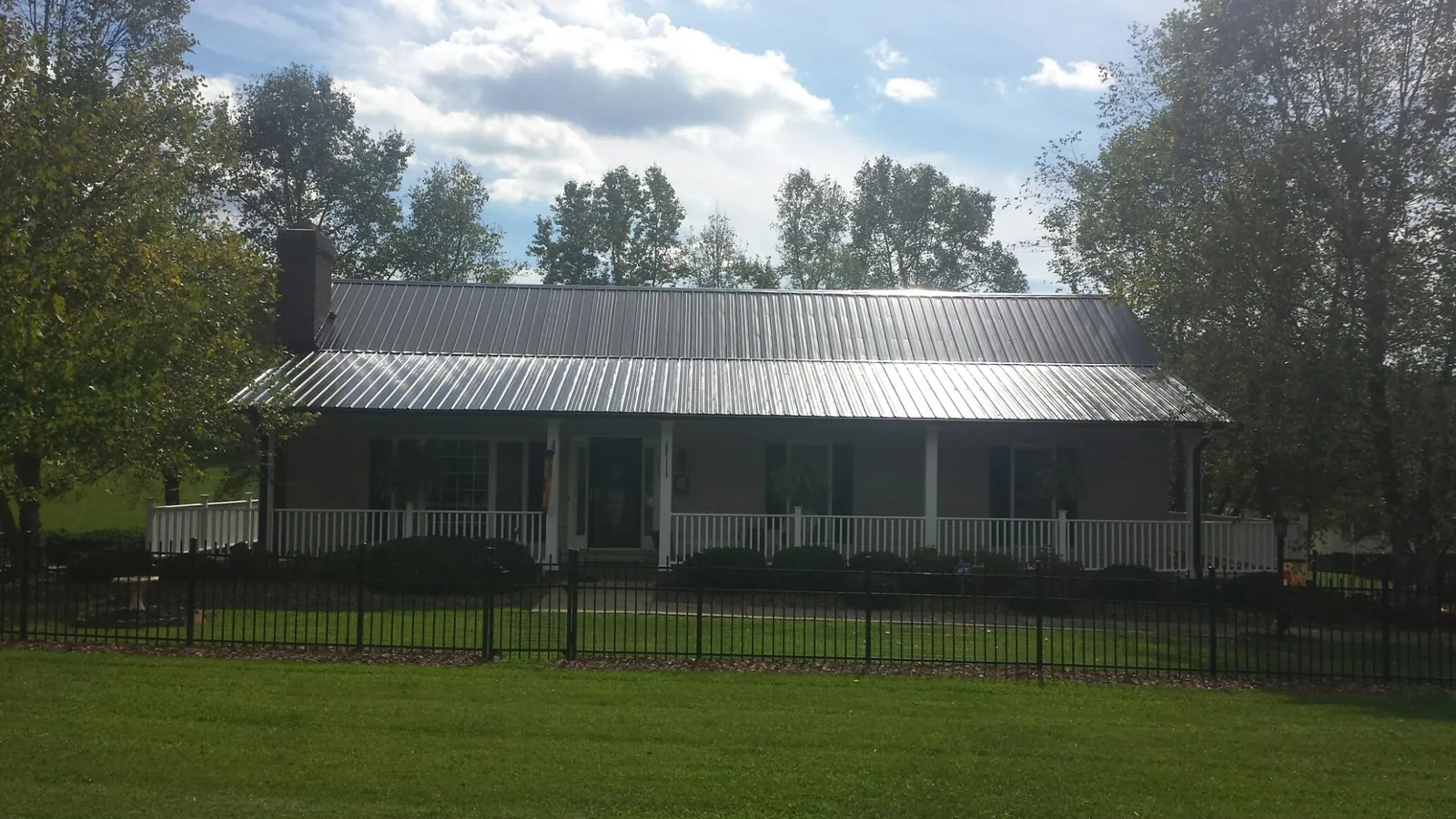 Gray metal roof on a brick ranch with a full width front porch — Gutter Guard Installation work by our crew in Thorp
