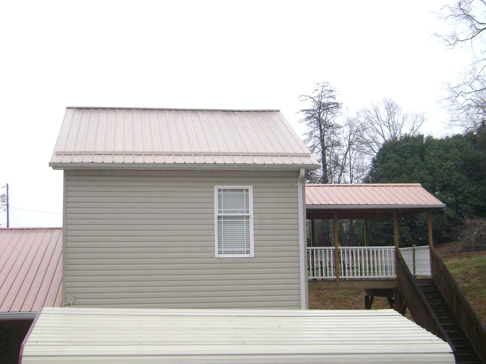 Tan metal roofs on a two story addition and attached porch, from a Roof Replacement job in Thorp